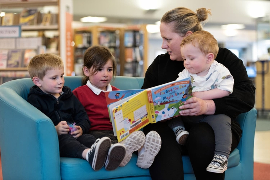 a lady reading books to children in a library