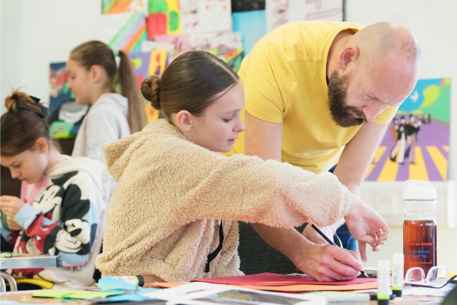 a man helping a young girl with an arts session in the library