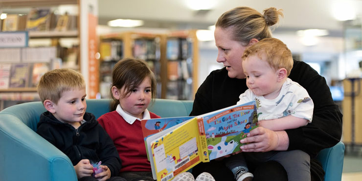 A mother reading to young children in a library