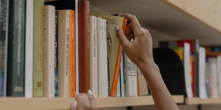 Woman's hands reaching for a book in a library
